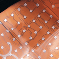 Close-up of a transparent sheet with vcsel smt lasers printed circuit board patterns on an orange background